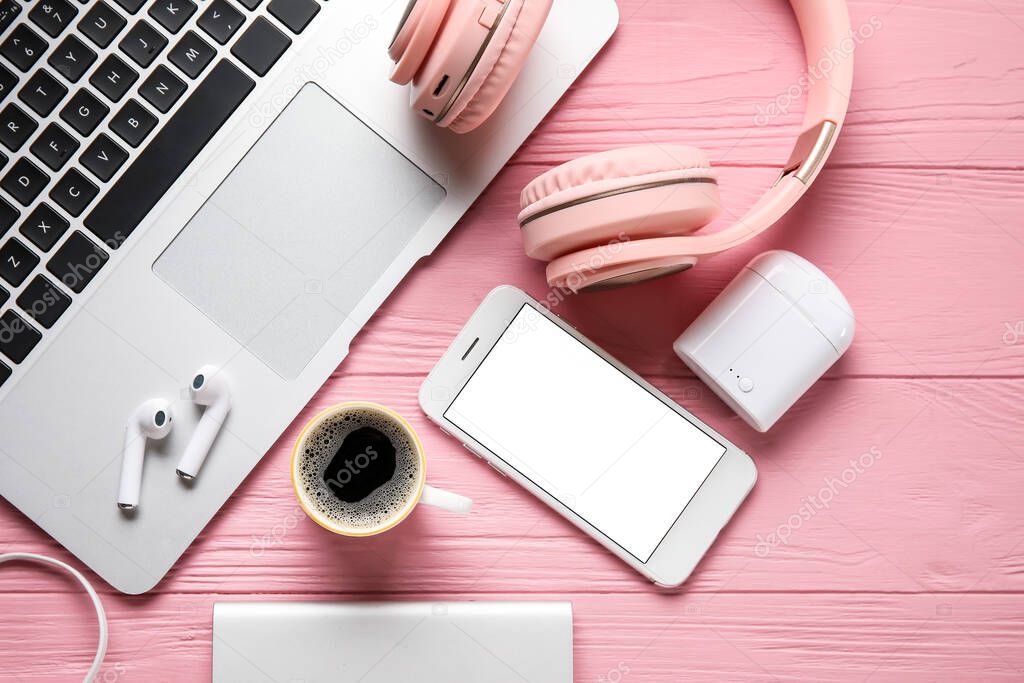 Different modern devices and cup of coffee on color wooden background