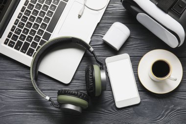 Farklı modern cihazlar ve koyu ahşap arka planda bir fincan kahve.