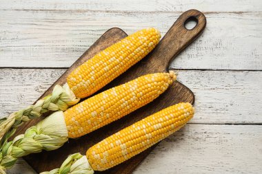 Hafif ahşap zemin üzerinde taze mısır koçanları olan tahta.