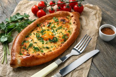 Ahşap arka planda lezzetli Ajarian Khachapuri parşömeni.