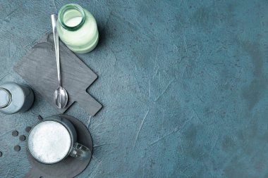 Bir bardak lezzetli kömür latte ve koyu arkaplanda sütlü bir şişe.