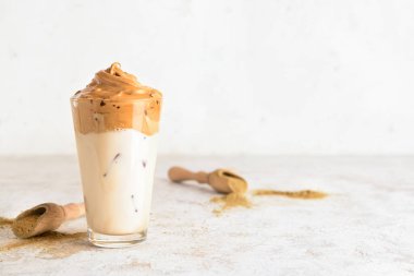 Bir bardak lezzetli dalgona hojicha latte ve hafif arka planda pudra.