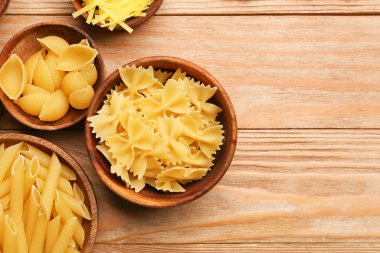 Ahşap zemin üzerinde farklı türde pişmemiş makarna olan kaseler.