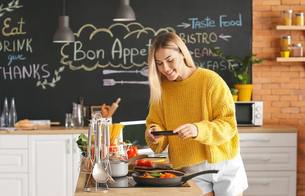 女食品摄影师 手持手机 在厨房里拍摄美味油炸蔬菜的照片 — 图库照片