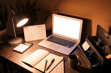 Renkli duvarın yanında parlayan lamba ve bilgisayarlı modern işyeri