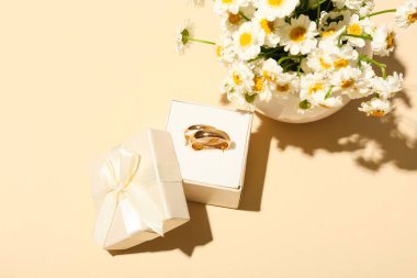 Evlilik yüzükleriyle dolu bir kutu ve renkli arkaplanda güzel çiçekler olan vazo.