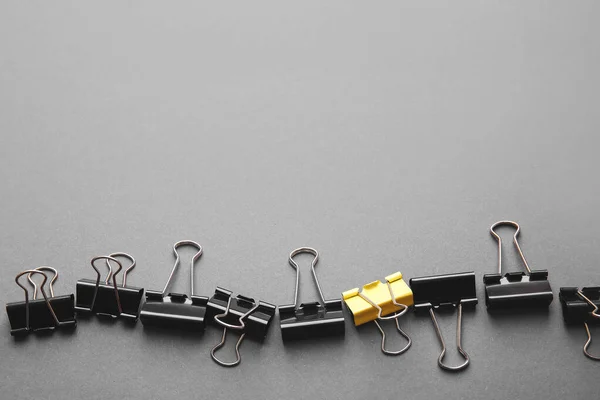 Yellow Paper Clip Black Ones Grey Background Concept Uniqueness — Stock Photo, Image