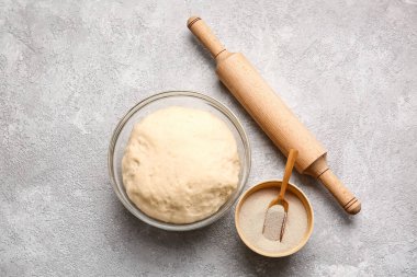 Taze hamurlu kase, kuru maya ve hafif arka planda merdane.