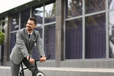 İş adamı şehir caddesinde bisikletle işe gidiyor.