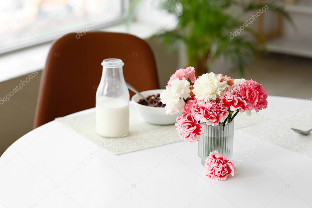 Vase with flowers on dining table in kitchen