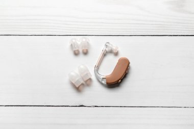 Beyaz ahşap arka planda işitme cihazı ve aksesuarlar