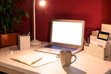 Renkli duvarın yanında parlayan lamba ve bilgisayarlı modern işyeri