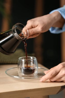 Kadın sıcak Türk kahvesini cam bardağa dolduruyor.
