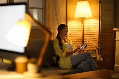 Akşamları tablet bilgisayar kullanan genç bir kadın