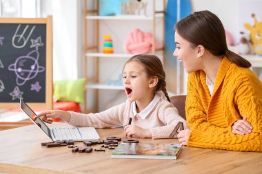 Speech therapist working with cute girl in clinic clipart