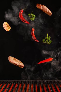 Flying beef brisket and vegetables over grill on dark background clipart