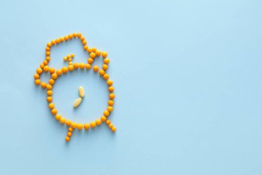 Renk arkaplanındaki haplardan yapılmış çalar saat