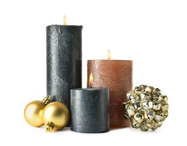 Beyaz arka planda yanan mumlar ve Noel süslemeleri olan kompozisyon