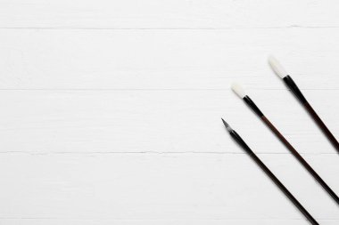 Beyaz ahşap zemin üzerinde kaligrafik fırçalar