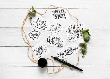 Farklı metin ile kağıt parçaları ve beyaz ahşap arka planda ucu kalem