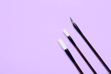 Leylak arkaplanındaki kaligrafik fırçalar