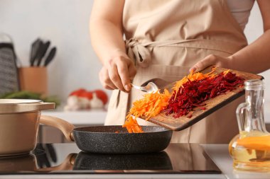 Mutfağa rendelenmiş havuç ve pancar koyan bir kadın.