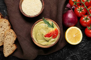 Lezzetli baba ghanoush 'lu kase, koyu arkaplanda ekmek ve sebze.