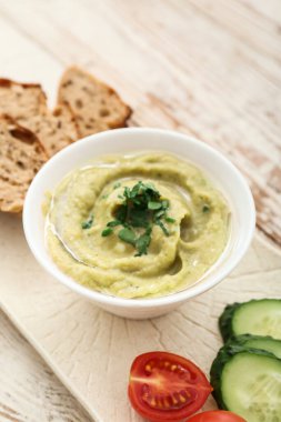 Lezzetli baba ghanoush 'lu kase, masada ekmek ve sebzeler, yakın plan.