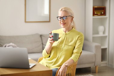 Ofiste kahve içen olgun bir kadın.