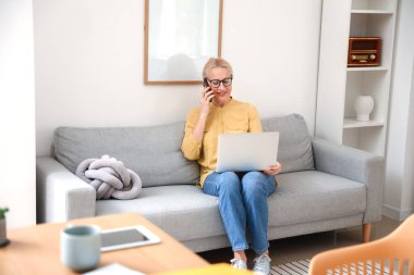 Ofisteki koltukta otururken bilgisayarla konuşan olgun bir kadın.