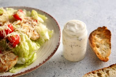 Lezzetli Sezar salatası ve soslu beyaz arka plan, yakın plan.