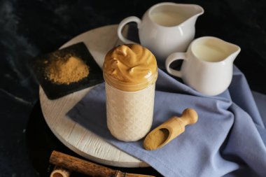 Koyu arkaplanda bir bardak lezzetli dalgona hojicha latte.