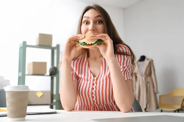 Female Seller Eating Tasty Vegan Burger Workplace — Stock Photo, Image