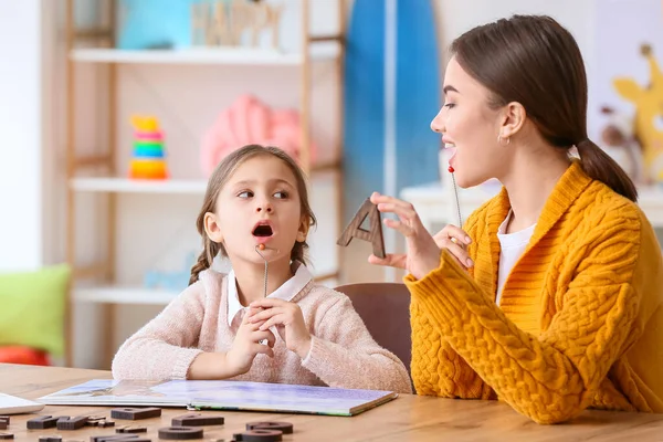 Speech therapist working with cute girl in clinic