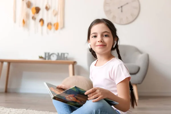 Liten Flicka Med Hörlurar Läser Bok Hemma — Stockfoto