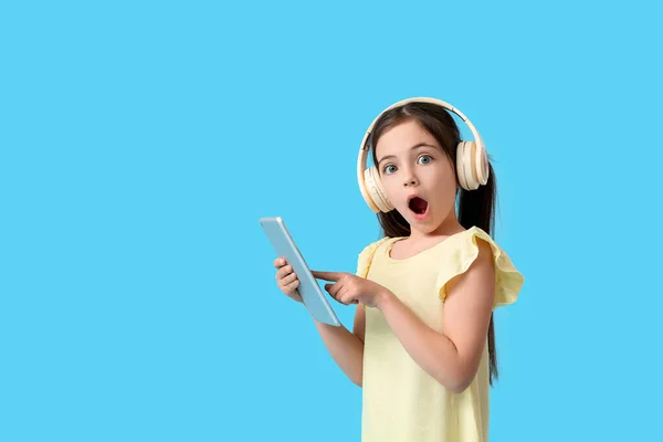 驚きの女の子とともにタブレットコンピュータとヘッドフォン上の色の背景 — ストック写真