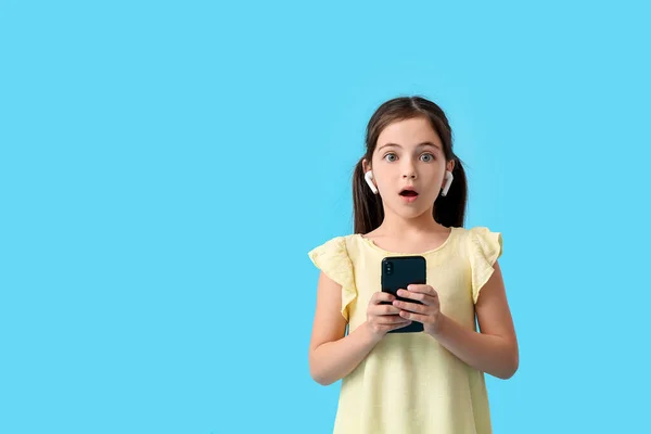 驚きの女の子とともにイヤホンと携帯電話上の色の背景 — ストック写真
