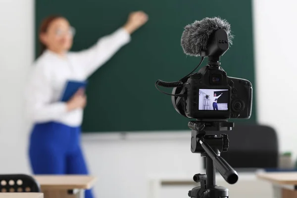 Teacher recording video for his students in classroom