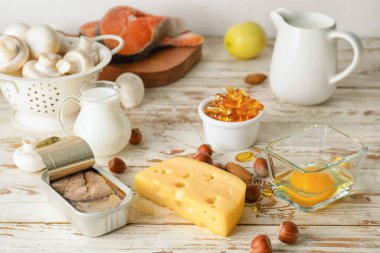 Hafif ahşap arka planda D vitamini içeren farklı sağlıklı ürünler.