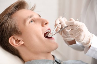 Diş teli takan yakışıklı bir adam klinikte ortodontiste gidiyor.