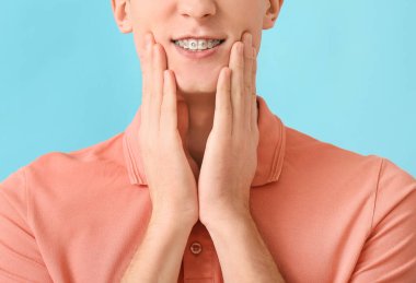 Arkaplanda diş teli olan yakışıklı bir adam, yakın plan.