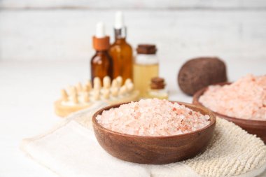 Deniz tuzu ve hafif ahşap arka planda gerekli yağ şişeleriyle güzel bir spa kompozisyonu, yakın plan.