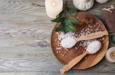 Deniz tuzu ve ahşap arka planda gerekli yağ şişeleriyle güzel bir spa kompozisyonu.