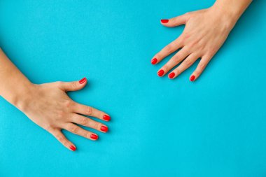 Mavi arka planda güzel manikürlü kadın elleri, yakın plan.