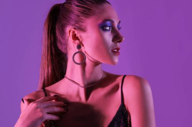 Koyu mor arka planda şık bir genç kadın.