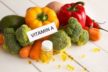 VITAMIN A 'ya beyaz ahşap arka planda sebze ve haplarla metin yaz