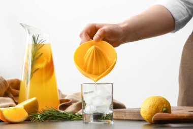 Kadın mutfaktaki masaya portakal suyu döküyor.