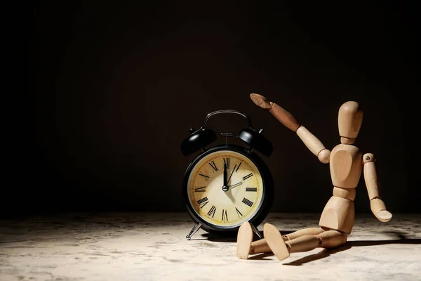 暗い背景に目覚まし時計と木製のマネキン — ストック写真