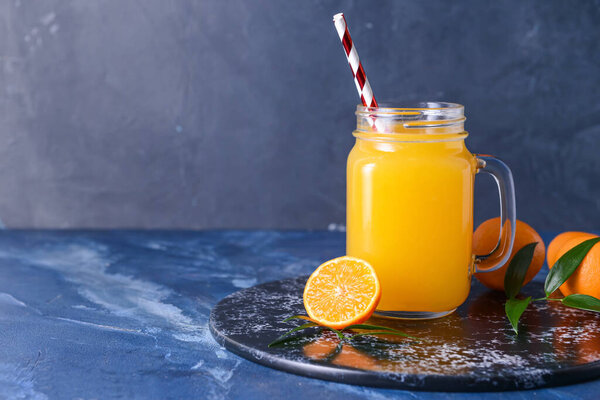 Mason jar with tasty mandarin juice on color background