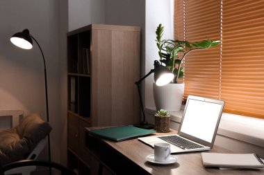 Pencerenin yanında dizüstü bilgisayarı olan modern işyeri